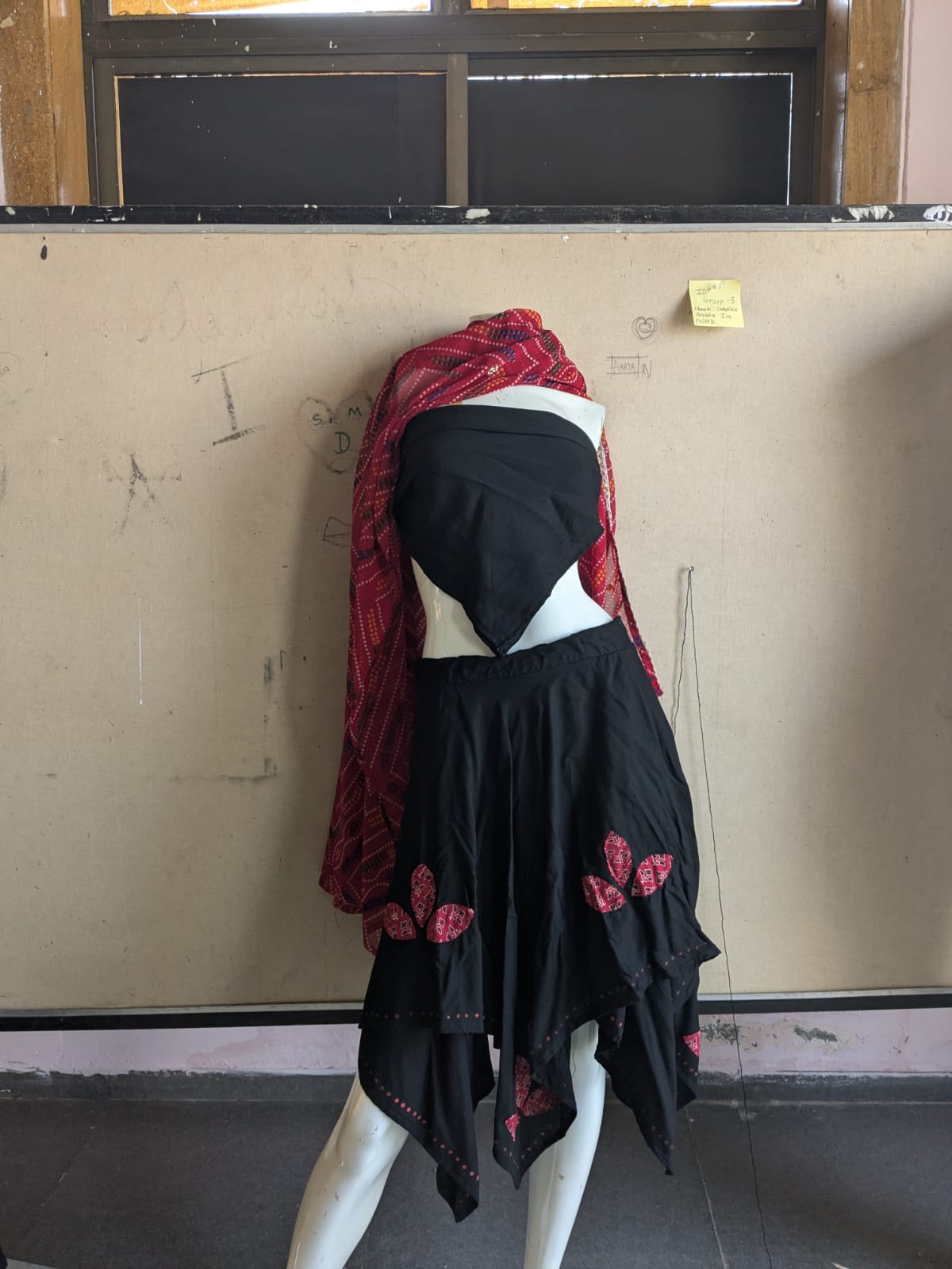 Bhil inspired mannequin look with black garment, red drape and asymmetric skirt